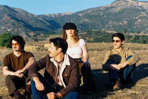 A lush outdoor scene with four young adults enjoying the California Strawberry Festival entertainmen.