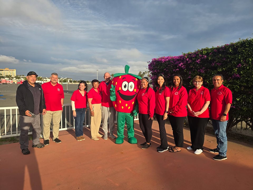 A colorful group photo with the California Strawberry Festival mascot and staff outdoors.