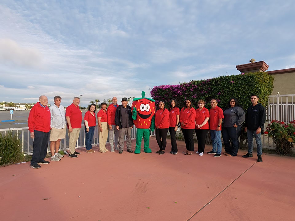 A colorful group of people with a strawberry mascot at the California Strawberry Festival.